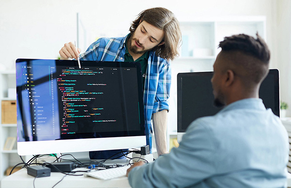 People working together at a computer with code on screen